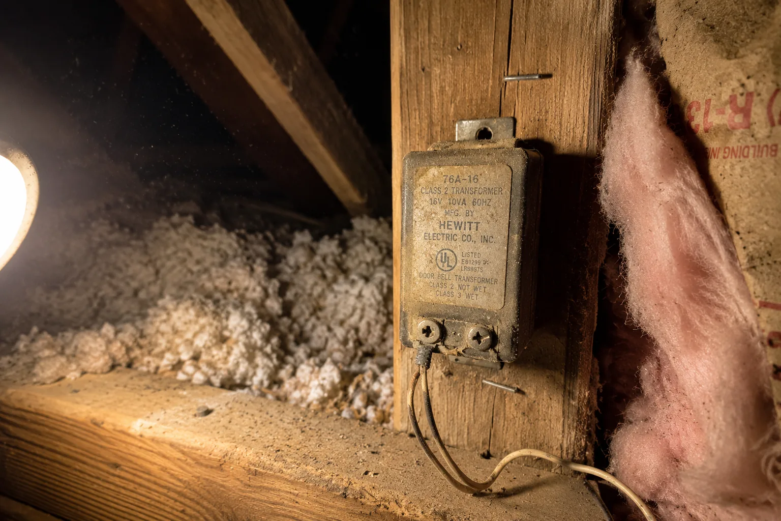 Old doorbell transformer mounted to a floor joist in a residential attic